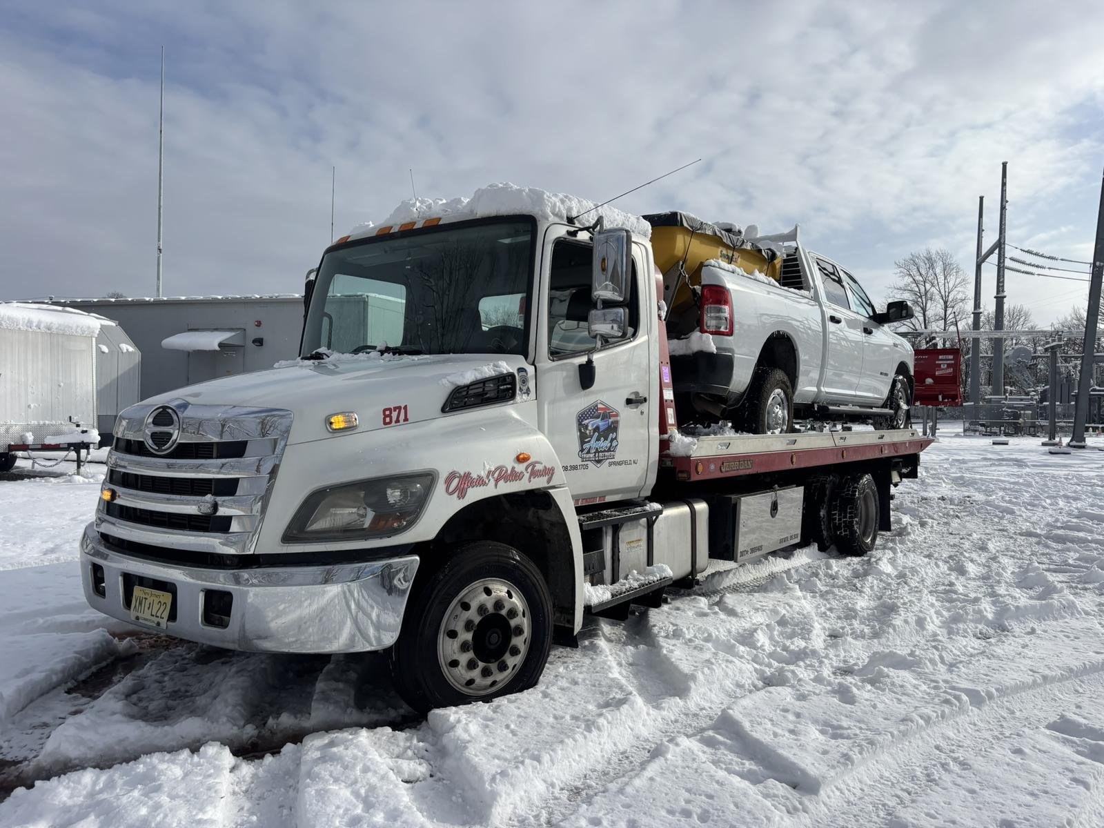 Ariel's Towing flatbed hauling a pickup truck after a snowstorm in NJ